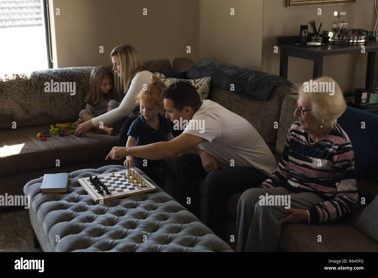 Multi generation family playing games on sofa in living room Banque D'Images