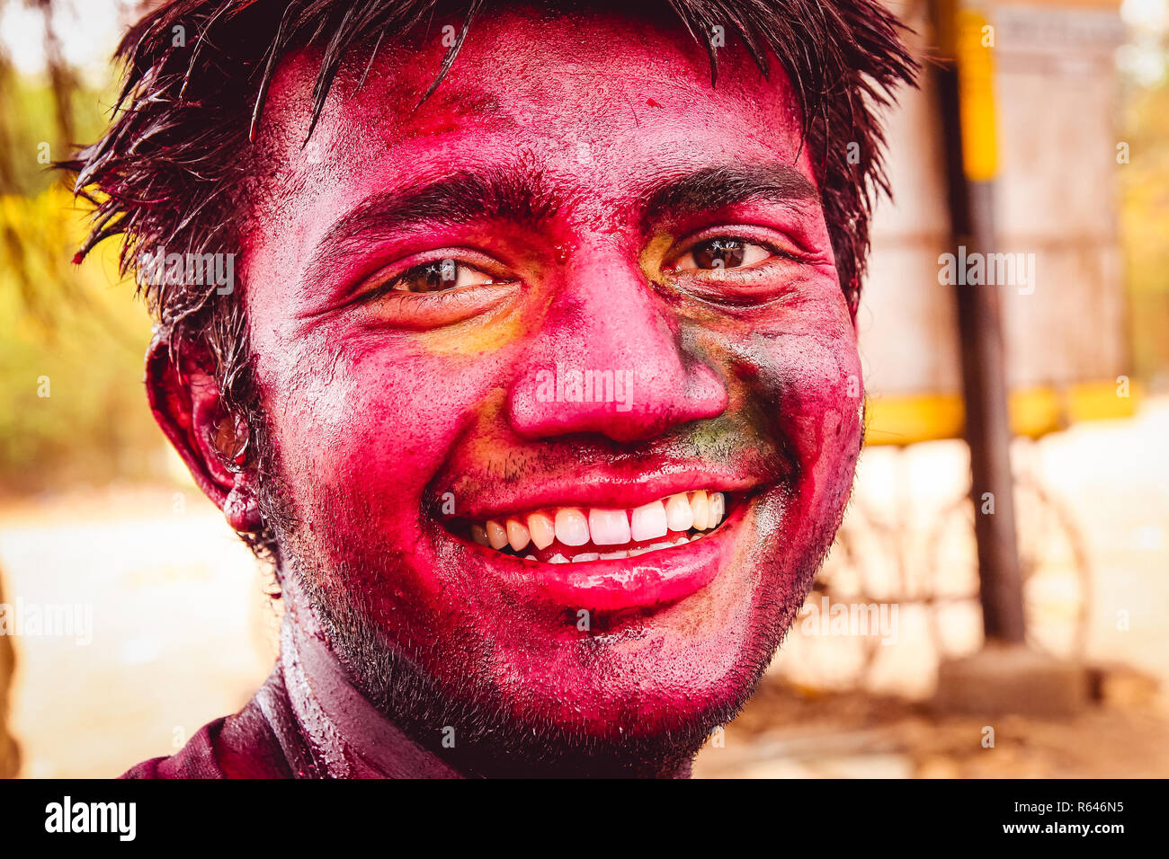 New Delhi, Inde - 10 mars 2016 : close up portrait of young, heureux, l'homme indien avec un grand sourire et le visage plein de poudre de couleur à la caméra dans duri Banque D'Images