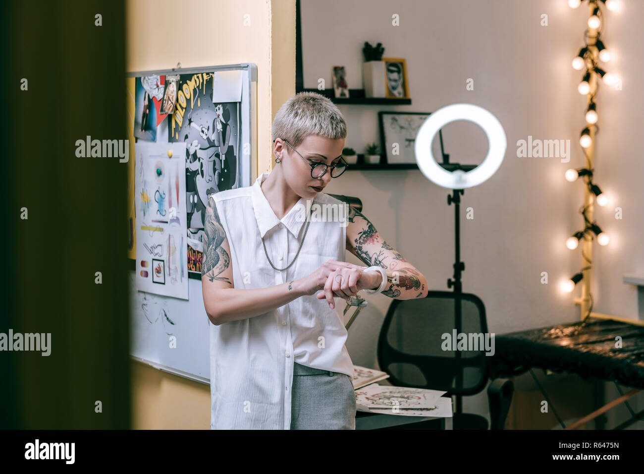 Les jeunes femmes bien debout dans le cabinet de maître de tatouage Banque D'Images
