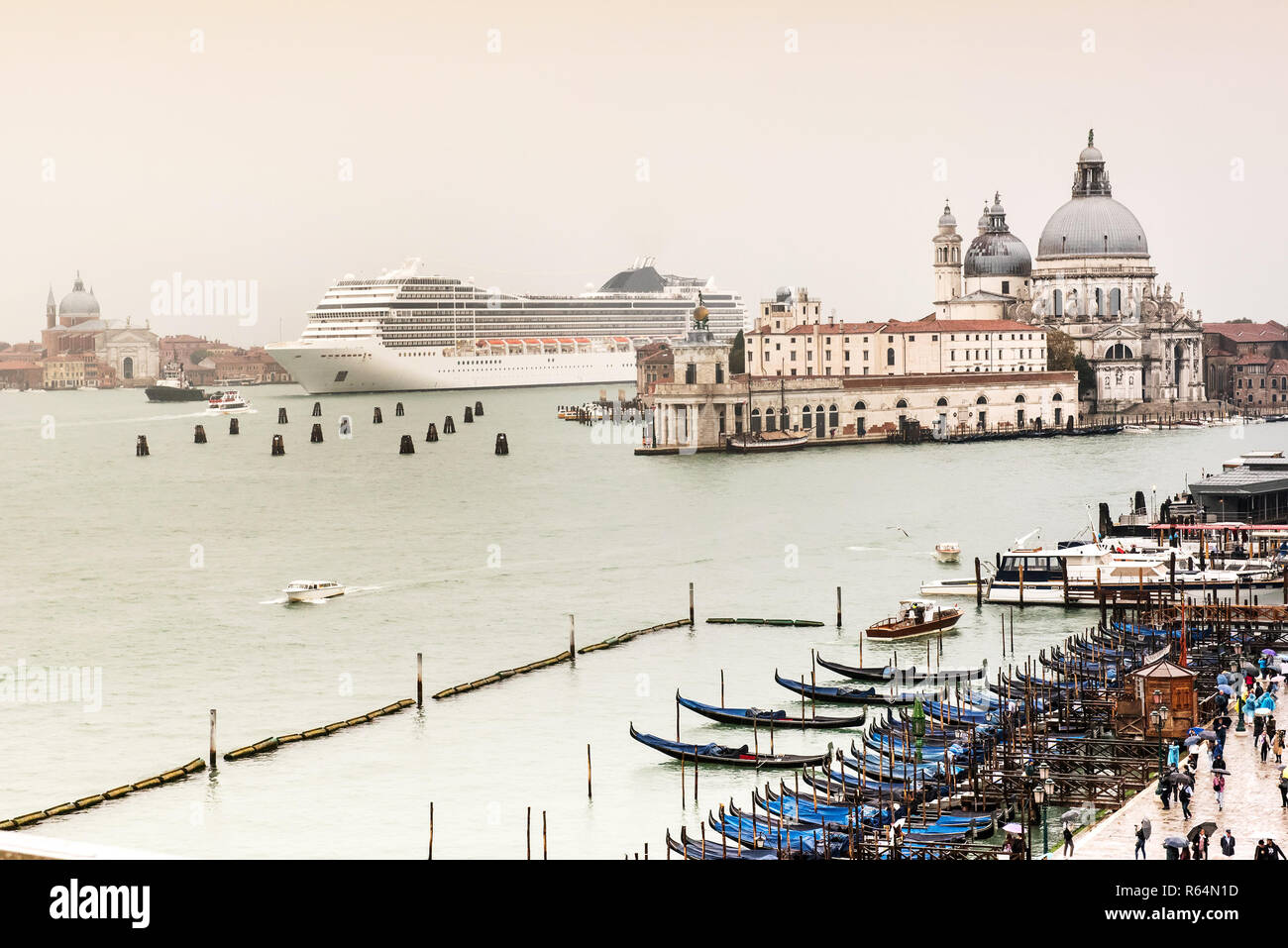 Big White de croisière de venir à Venise, Italie. Contrairement à l'échelle montrant l'architecture locale et les petits bateaux en premier plan. Journée nuageuse avec ciel gris Banque D'Images