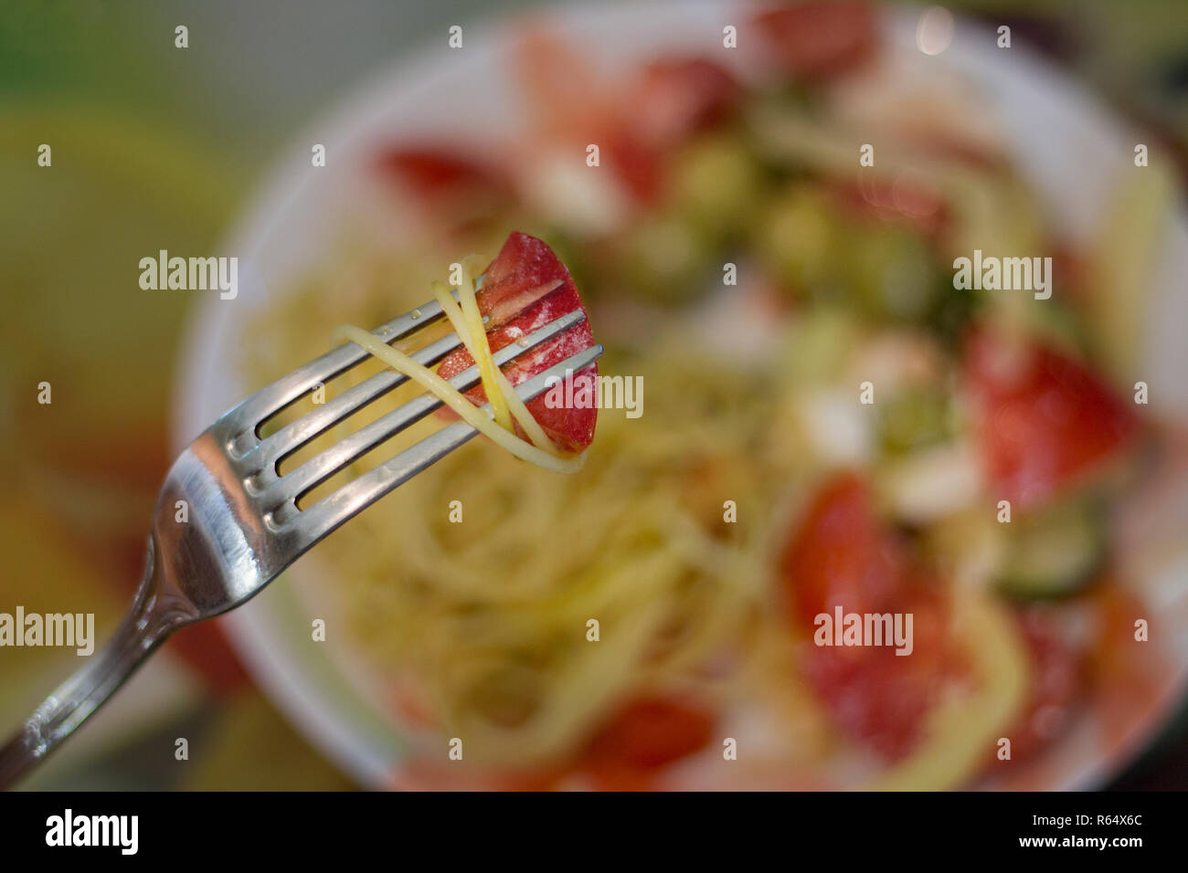 Avec la Tomate et pâtes spaghetti sur fourche avec salade végétarienne sur fond flou. Soft focus avec arrière-plan flou Banque D'Images
