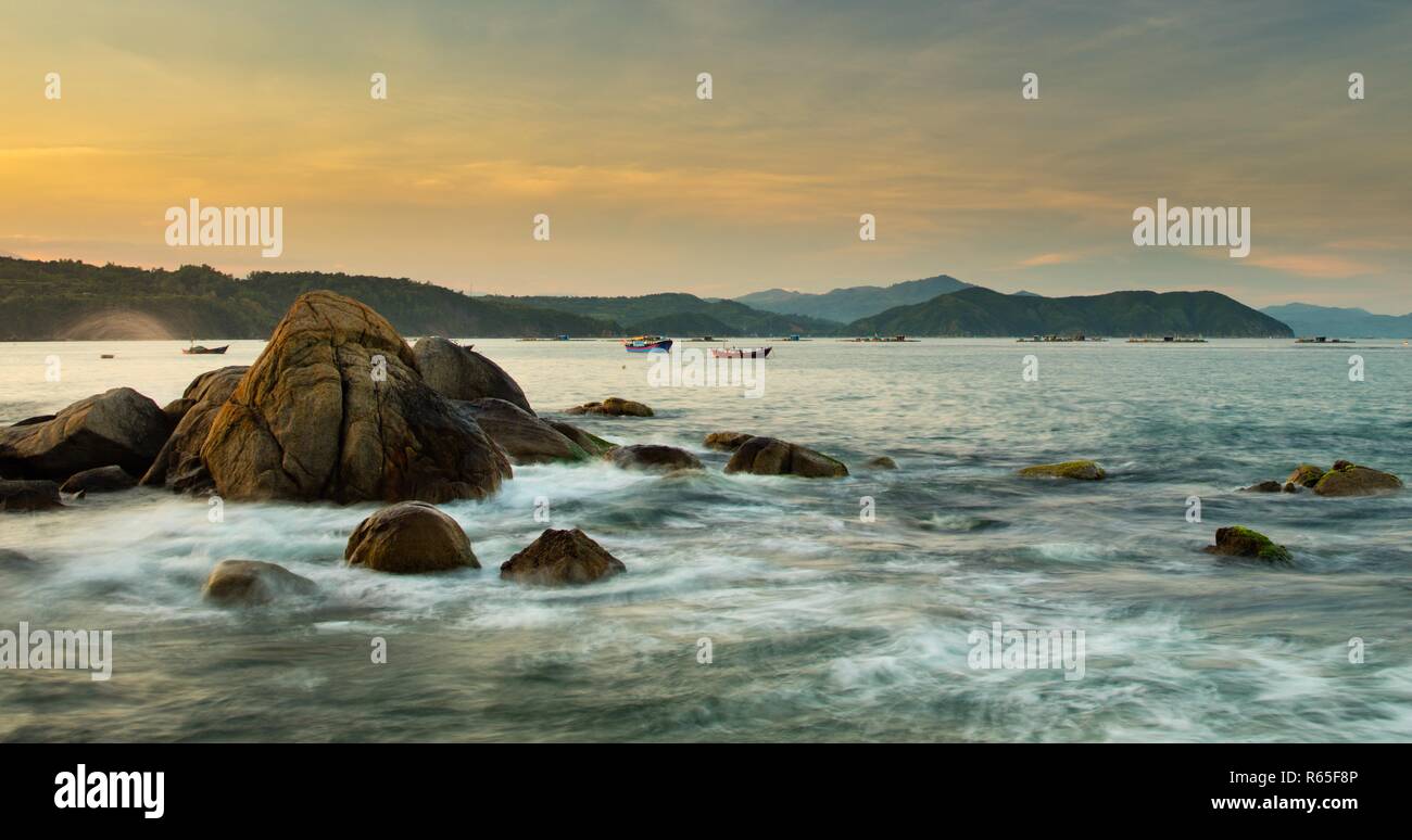 Ciel coloré sur une côte rocheuse au lever du soleil avec vue sur la mer de Chine du sud à Lam Bay au Vietnam. Banque D'Images