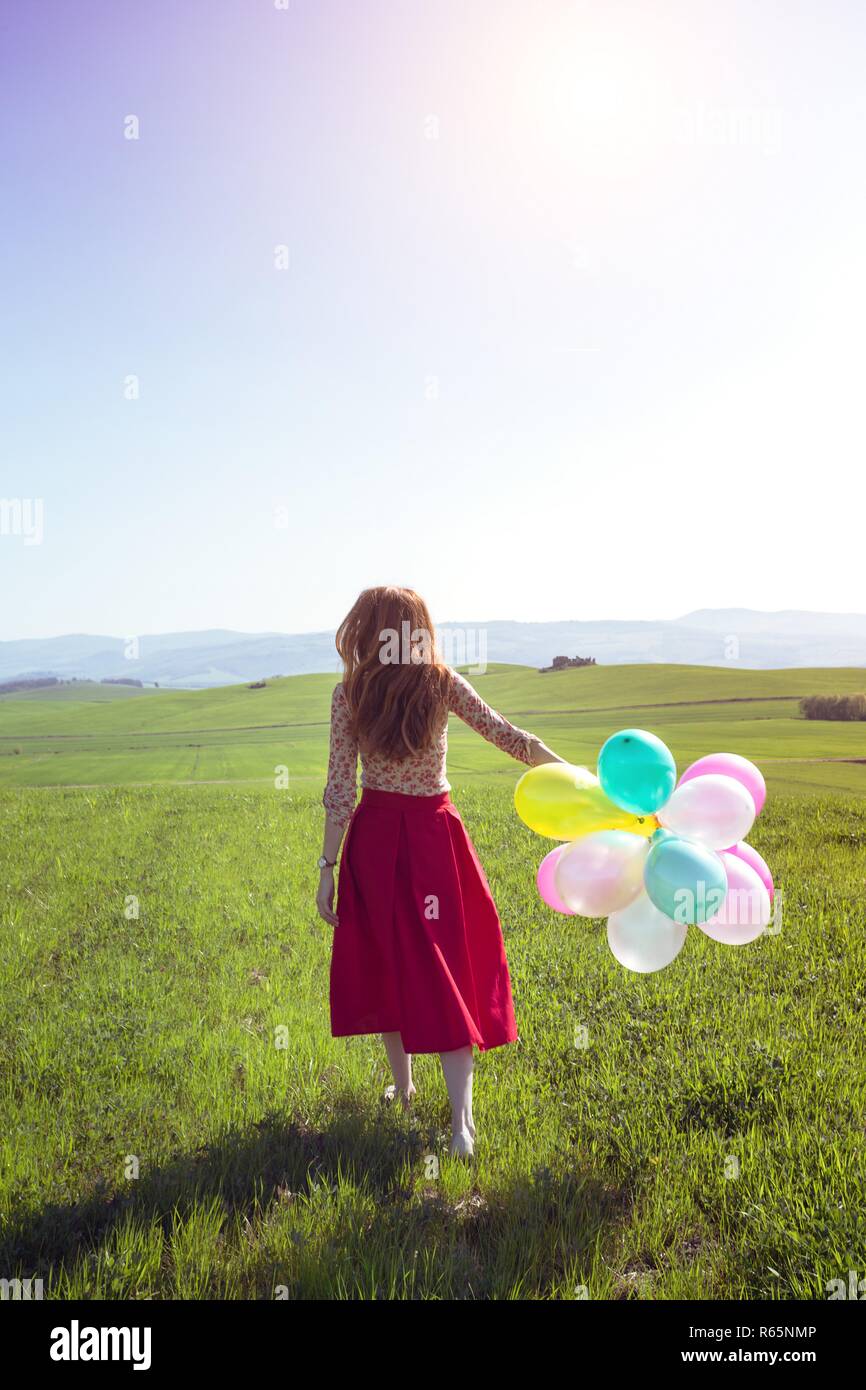 Happy girl dans les prés avec des ballons colorés toscans, contre le ciel bleu et vert prairie. La toscane, italie Banque D'Images