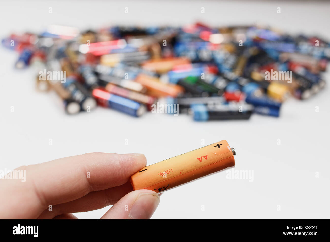 Arkhangelsk, Russie, le 3 décembre 2018 : Concept de recyclage. Batterie alcaline dans la main et beaucoup de piles alcalines flou en arrière-plan Banque D'Images