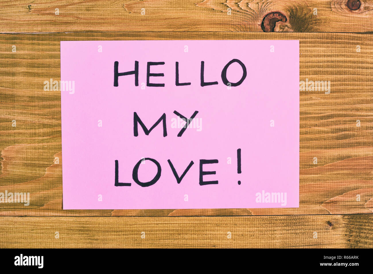 Message salut mon amour sur du papier rose sur la table en bois. Banque D'Images