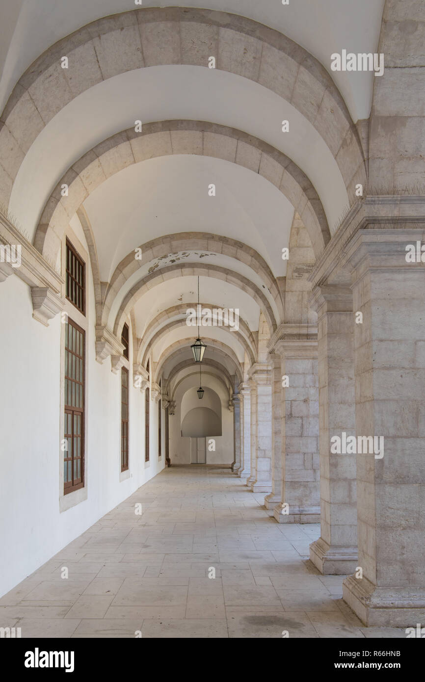 Déménagement à long couloir sous la perspective des arcs avec colonnes sur un côté et un mur blanc de l'autre côté de Lisbonne, Portugal - verticale Banque D'Images