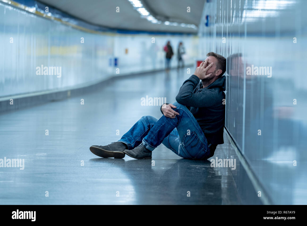 Jeune homme triste à pleurer de souffrance stress dépression assis sur sol street subway tunnel à leaning on wall désespérément seul dans le trouble mental Emo Banque D'Images