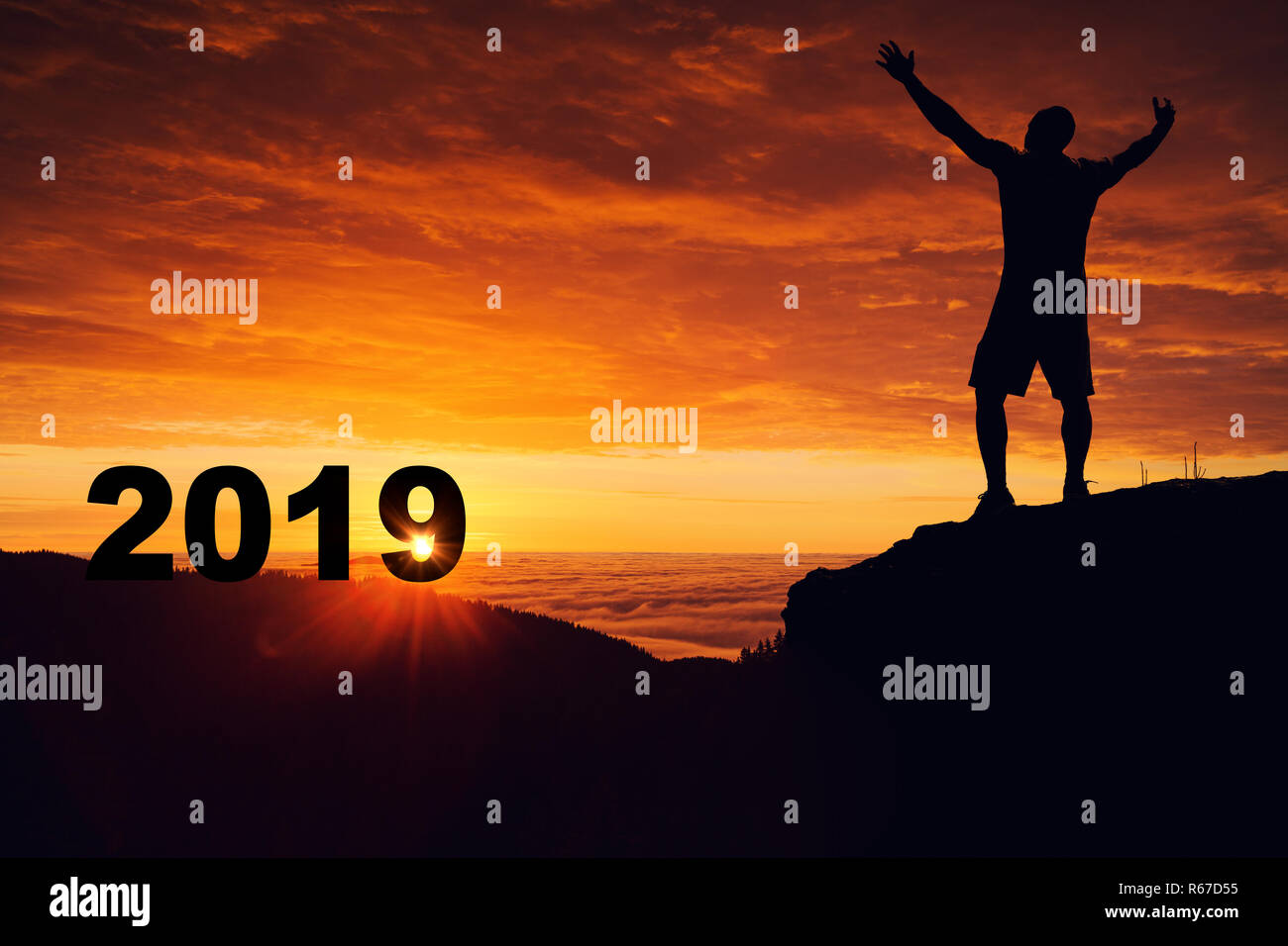 L'homme silhouette sur le sommet de la montagne en regardant le lever du soleil et 2019 ans alors qu'il célèbre. Banque D'Images