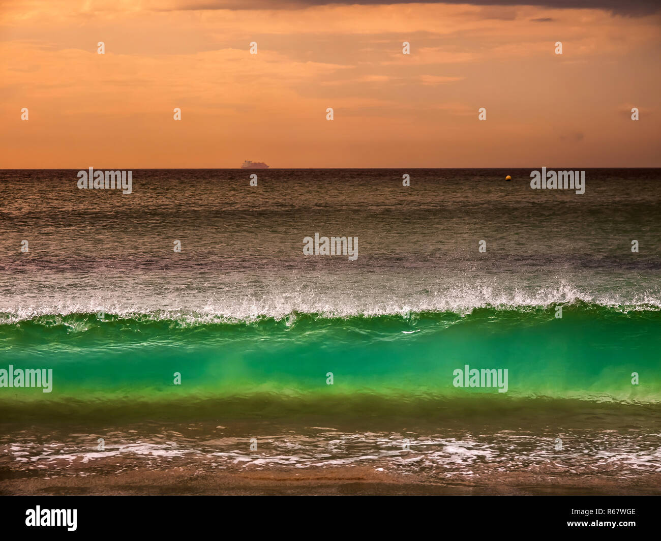 Les vagues sur la plage de sable fin au coucher de soleil Banque D'Images