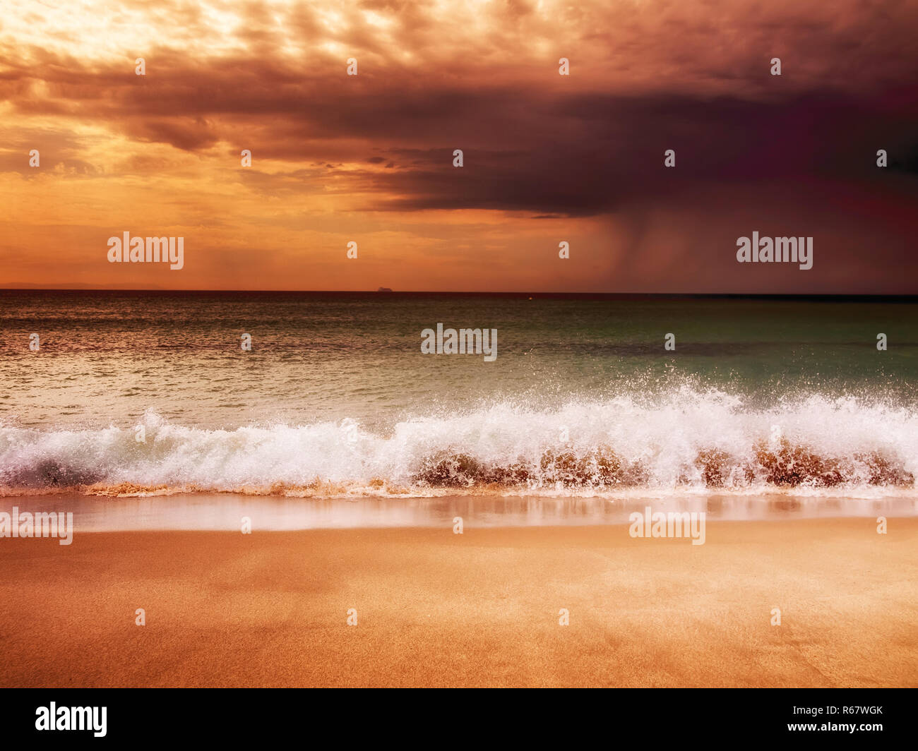 Les vagues sur la plage de sable fin au coucher de soleil Banque D'Images
