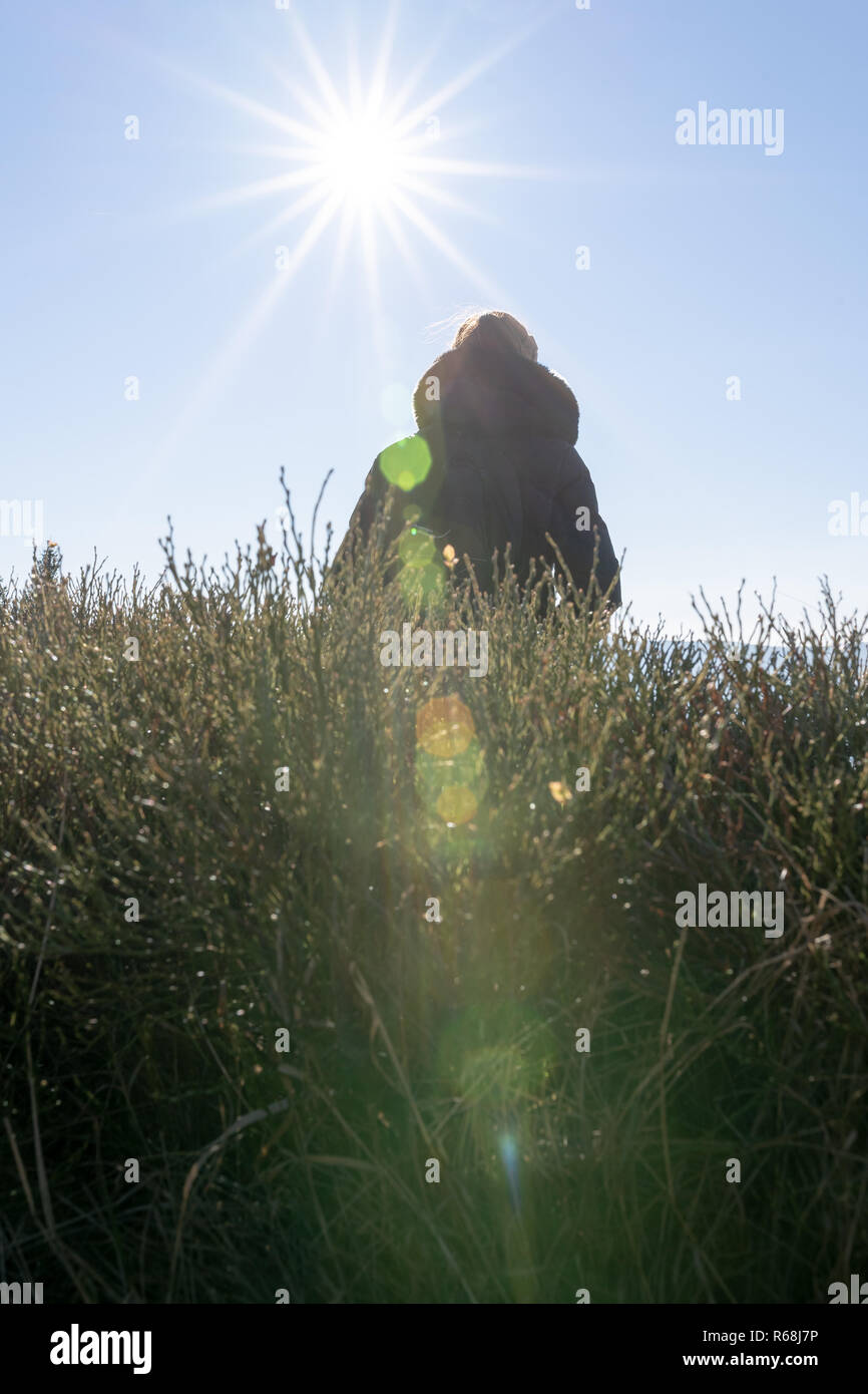 Jeune femme assise sur un banc éclairé par LED contre la lumière du soleil avec de lourdes. lens-flare Banque D'Images