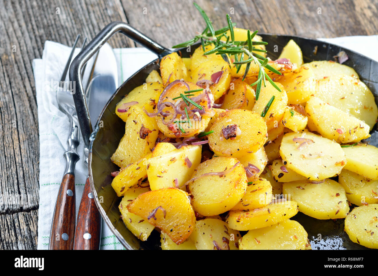 Pommes de terre sautées avec des oignons et des petits lardons dans une poêle de fer Banque D'Images