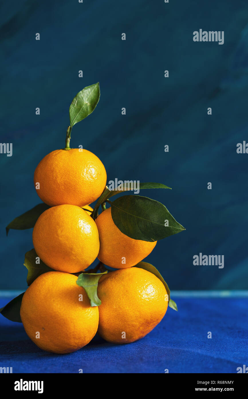 Haute pile des mandarins avec feuilles jaune est allongé sur fond bleu. Banque D'Images