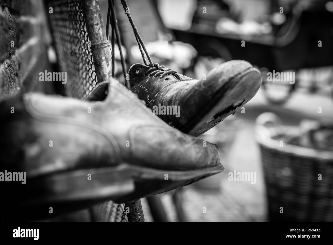 Porter des chaussures en cuir marron avec des trous dans les semelles, hanging on old vintage clôture avec les lacets attachés Banque D'Images