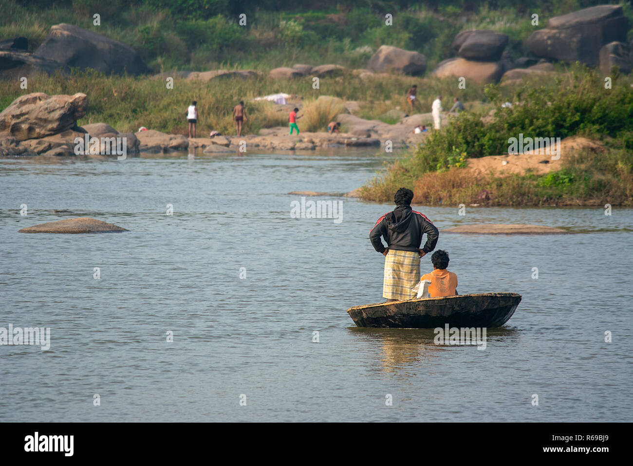Deux hommes utilisent un Coracle traditionnels voile pour traverser la rivière Tungabhadra, Punchline, Inde. Banque D'Images