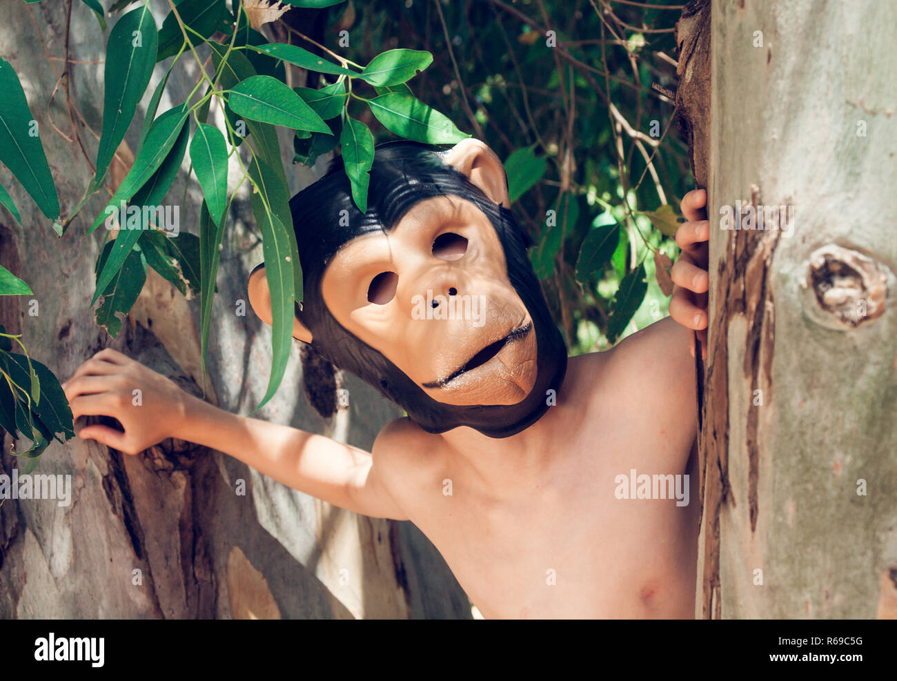 Shirtless Boy avec masque singe dans un parc Banque D'Images