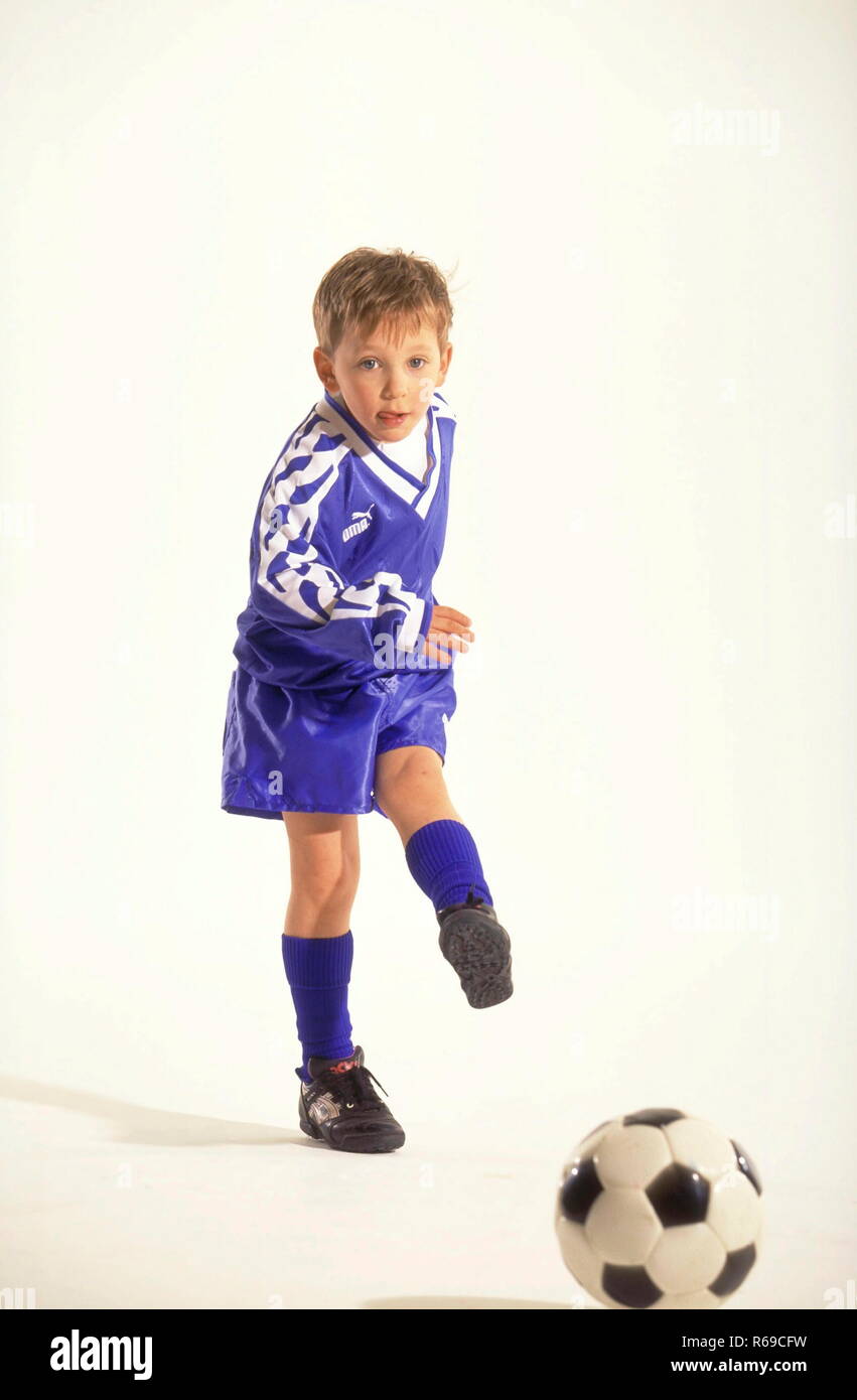 Portrait, Ganzfigur, Junge mit kurzen blondn Haaren, Fussballer, 8 Jahre, bekleidet mit blauem Trikot und Stutzen beim Kicken des balles Banque D'Images