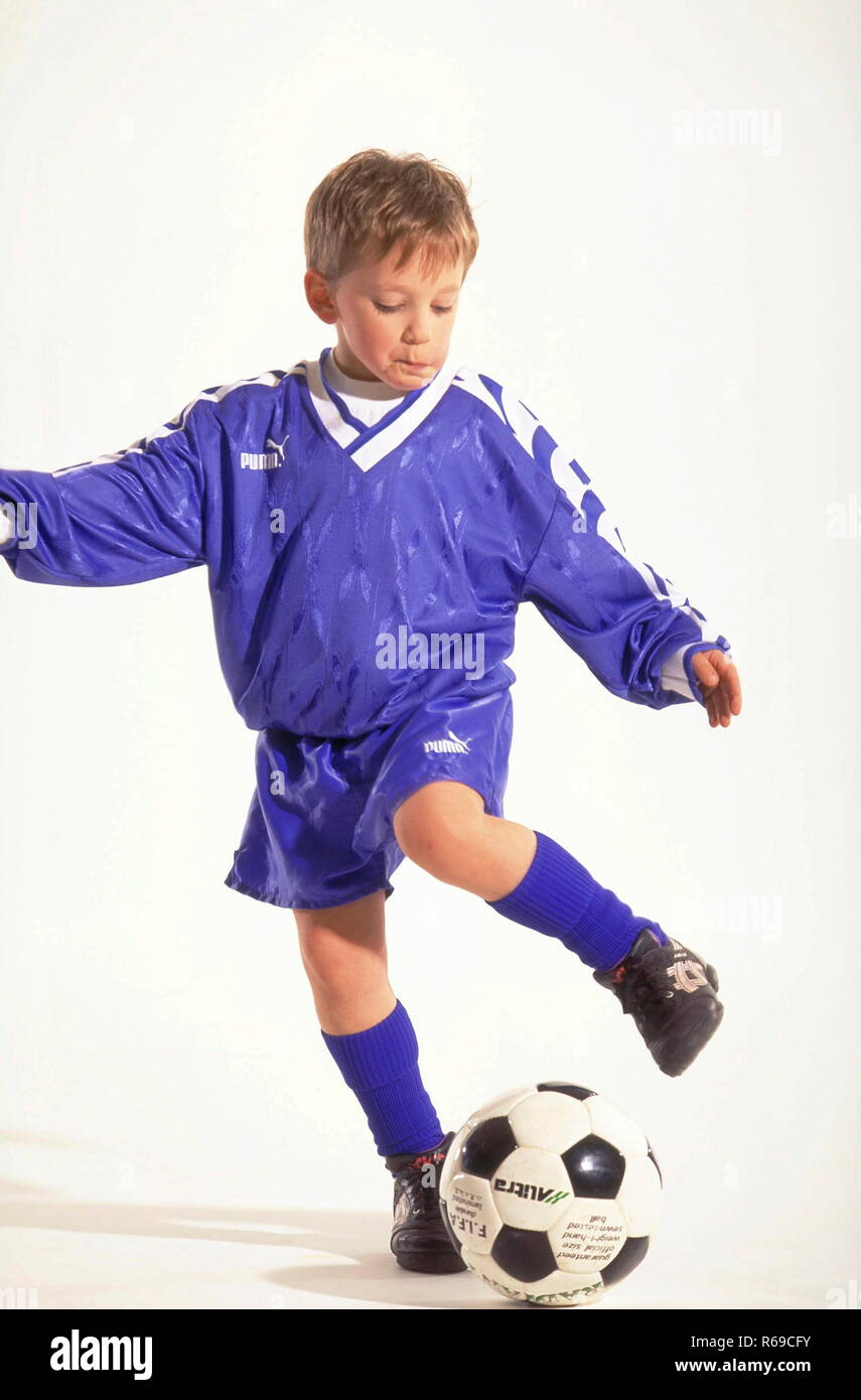 Portrait, Ganzfigur, Junge mit kurzen Haaren, Fussballer, 8 Jahre, bekleidet mit blauem Trikot und Stutzen beim Tribbeln mit dem Ball Banque D'Images