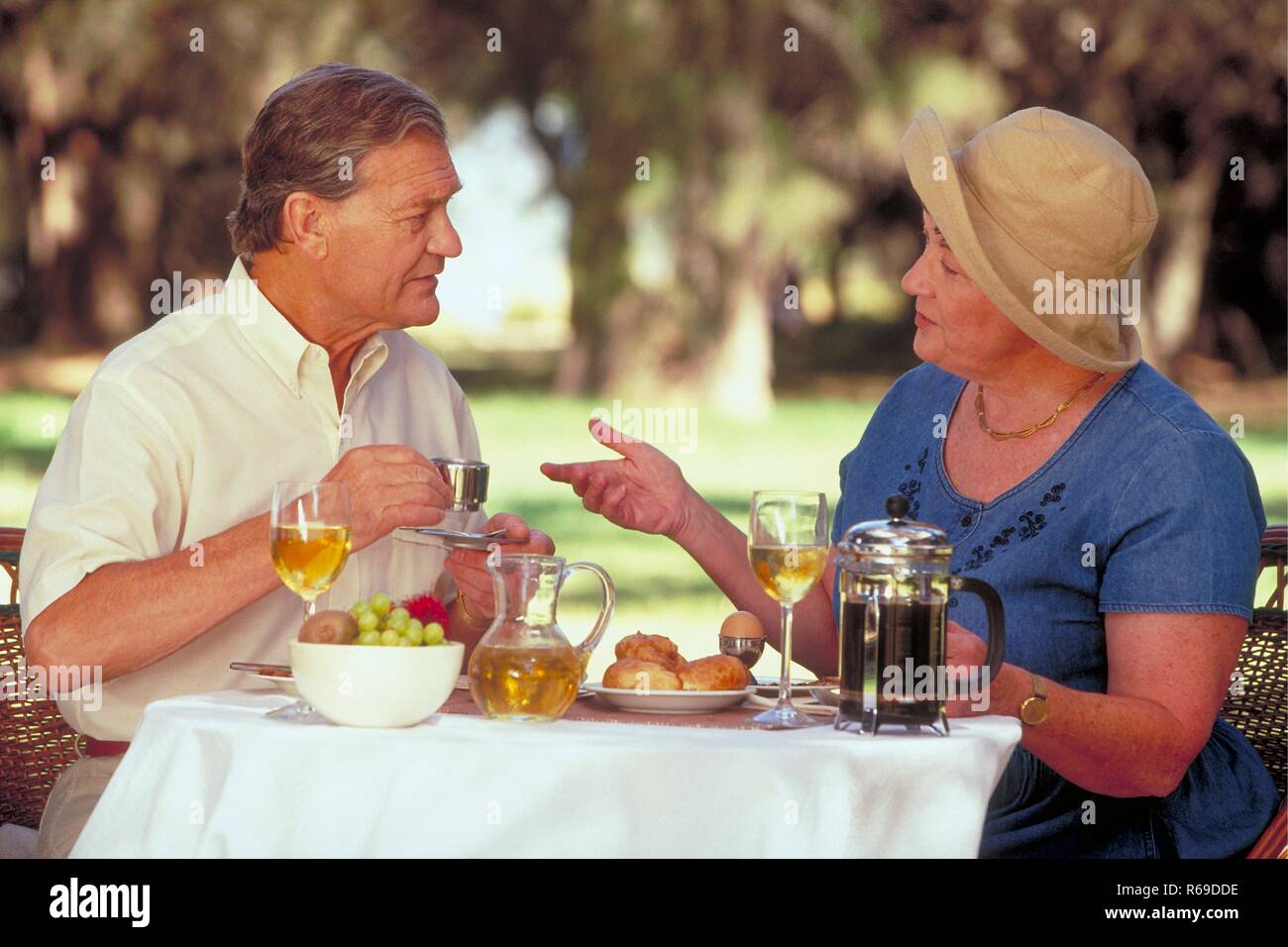 Seniorenpaar Halbfigur, Mitte 60 sitzt im Sommer im Garten beim Fruehstueck Banque D'Images