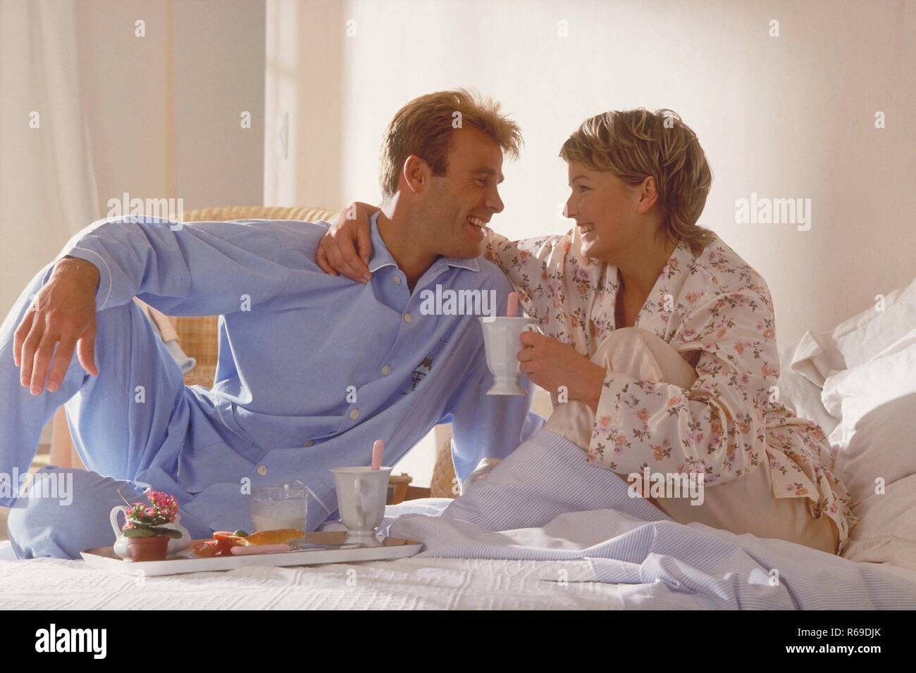 Portrait, Innenraum, Ganzfigur, junges Paar im Schlafanzug blondes sitzt Sonntagmorgens haus Fruehstueck im Bett Banque D'Images