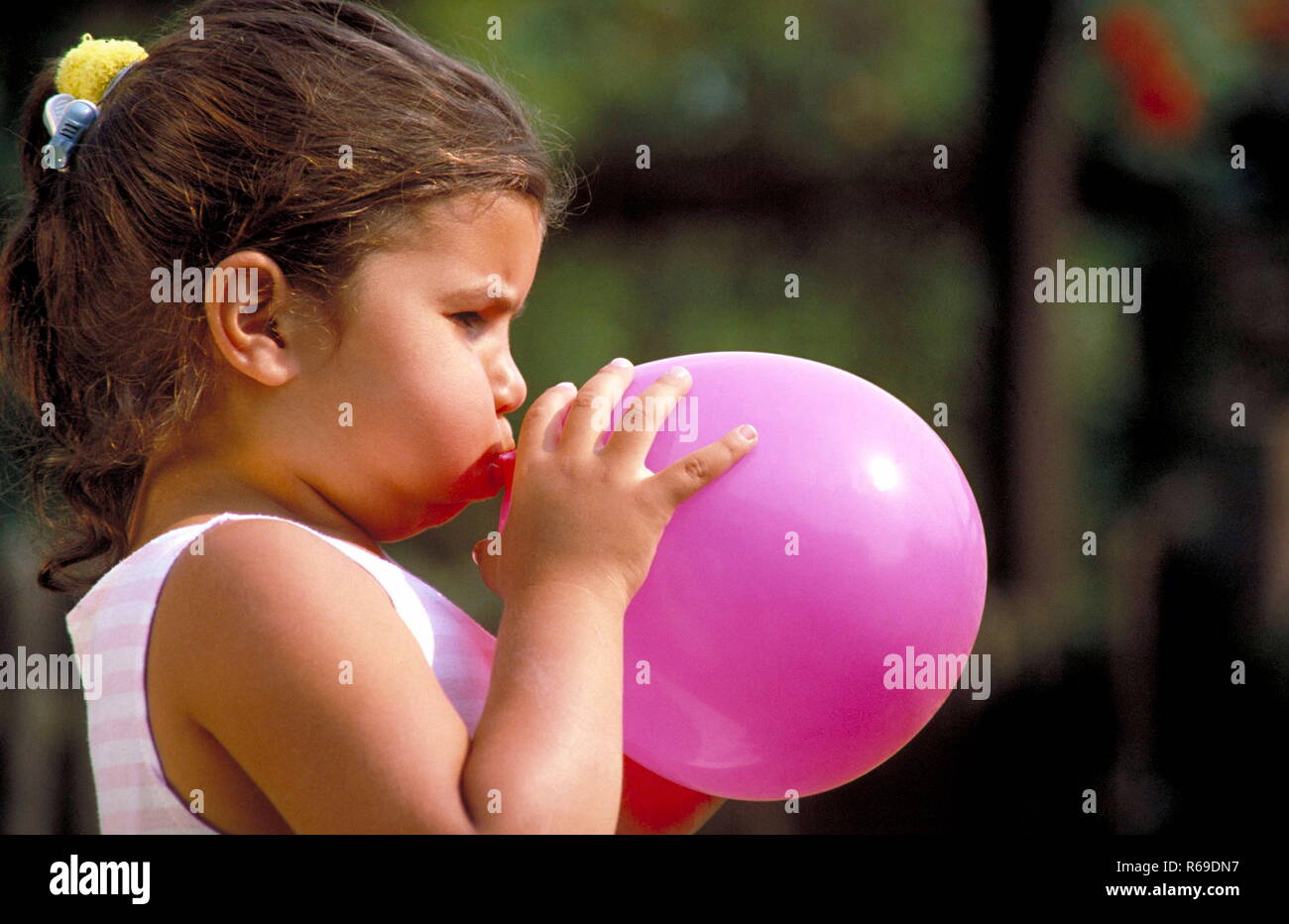 Profil, Nahaufnahme, extérieur, kleines bruenettes Maedchen mit Zopf blaest pinkfarbenen Luftballon auf einen Banque D'Images