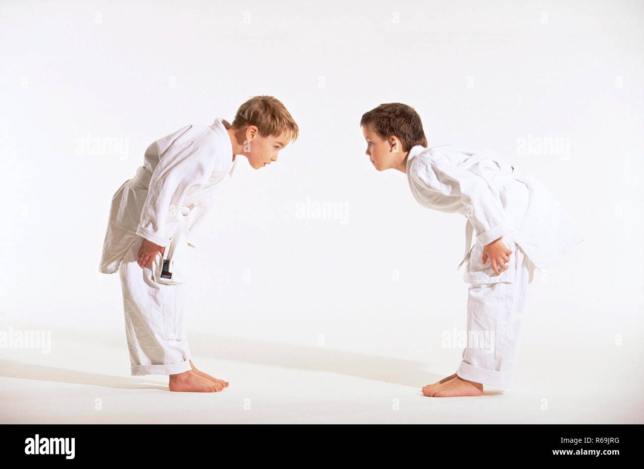 Portrait, Ganzfigur, 2 judoka, ein blonder und ein Junge asiatischer mit kurzen Haaren, 8 Jahre, Judoanzuegen verbeugen bekleidet mit sich zur Begruessung Banque D'Images