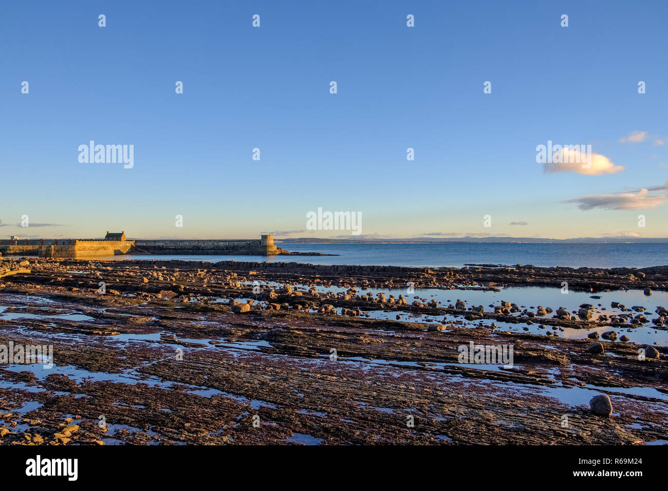 À la fin de la journée au coucher du soleil dans l'ouest de l'Écosse Saltcoats Pier à marée basse avec des réflexions à partir de la fin d'après-midi sur le mur de la jetée Banque D'Images