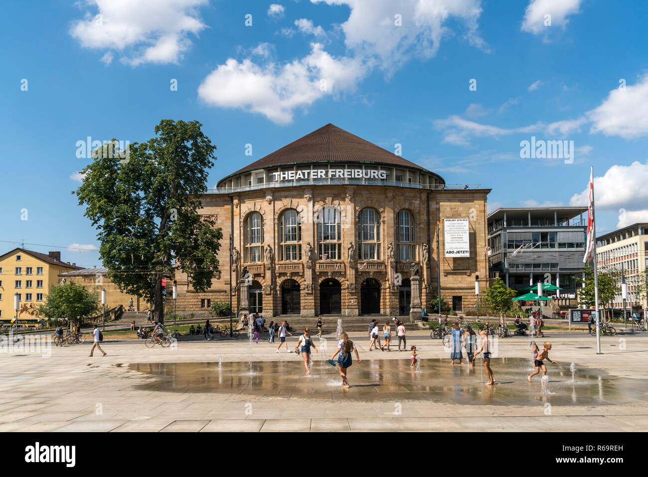 Enfants qui jouent à la fontaine en face du théâtre de la ville de Freiburg im Breisgau, Forêt-Noire, Bade-Wurtemberg, Allemagne Banque D'Images