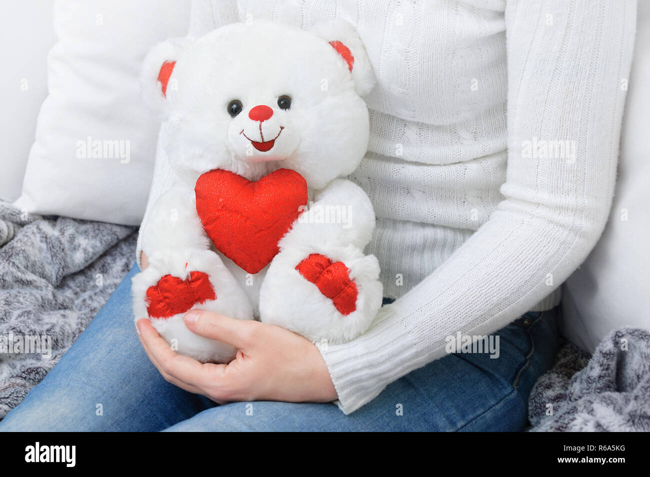 Une fille dans un chandail blanc holding a teddy ours blanc. Banque D'Images