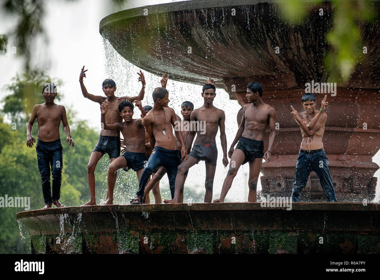 Un groupe de garçons et jeunes hommes se rafraîchir dans la fontaine près de la porte de l'Inde, un monument commémoratif de guerre du Canada à New Delhi, Inde. Banque D'Images