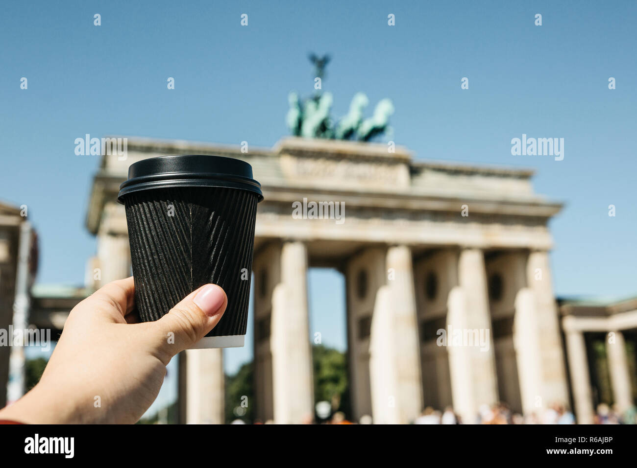 Une personne est titulaire d'un gobelet jetable avec du café ou une autre boisson sur l'arrière-plan de la porte de Brandebourg à Berlin en Allemagne lors d'une promenade à pied ou de visites. Banque D'Images