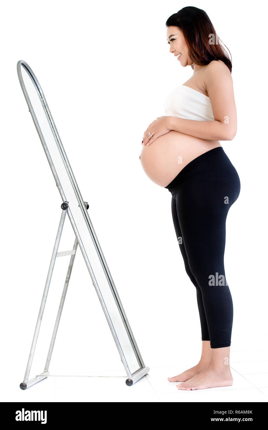 Smiling pregnant woman looking at mirror Banque D'Images