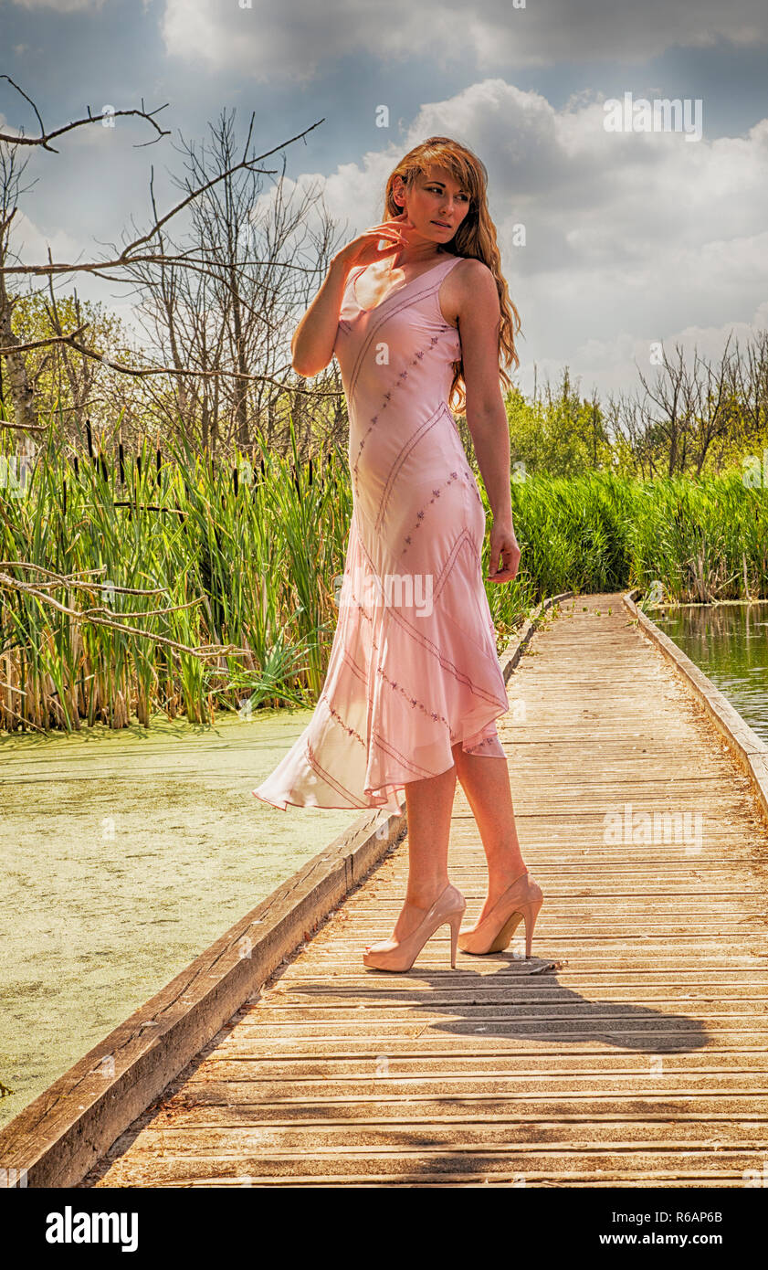 Dame portant robe d'été rose à bord de marche, mode poser Banque D'Images