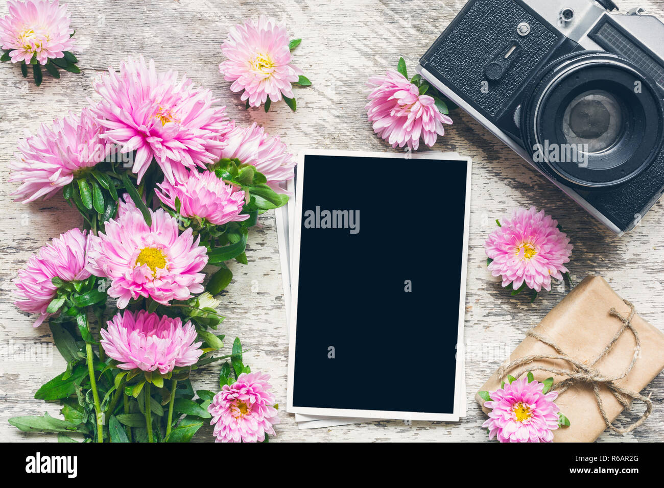 Cadre photo blanc retro vintage avec appareil photo et magnifique bouquet de fleurs et de l'aster rose boîte cadeau. maison de vacances ou de mariage contexte. maquette vue de dessus. Banque D'Images