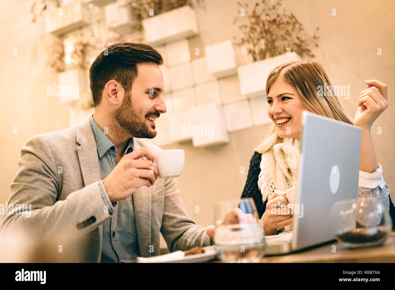 Deux jeunes smiling business people talking et travaillant sur un ordinateur portable sur une pause au café. Banque D'Images