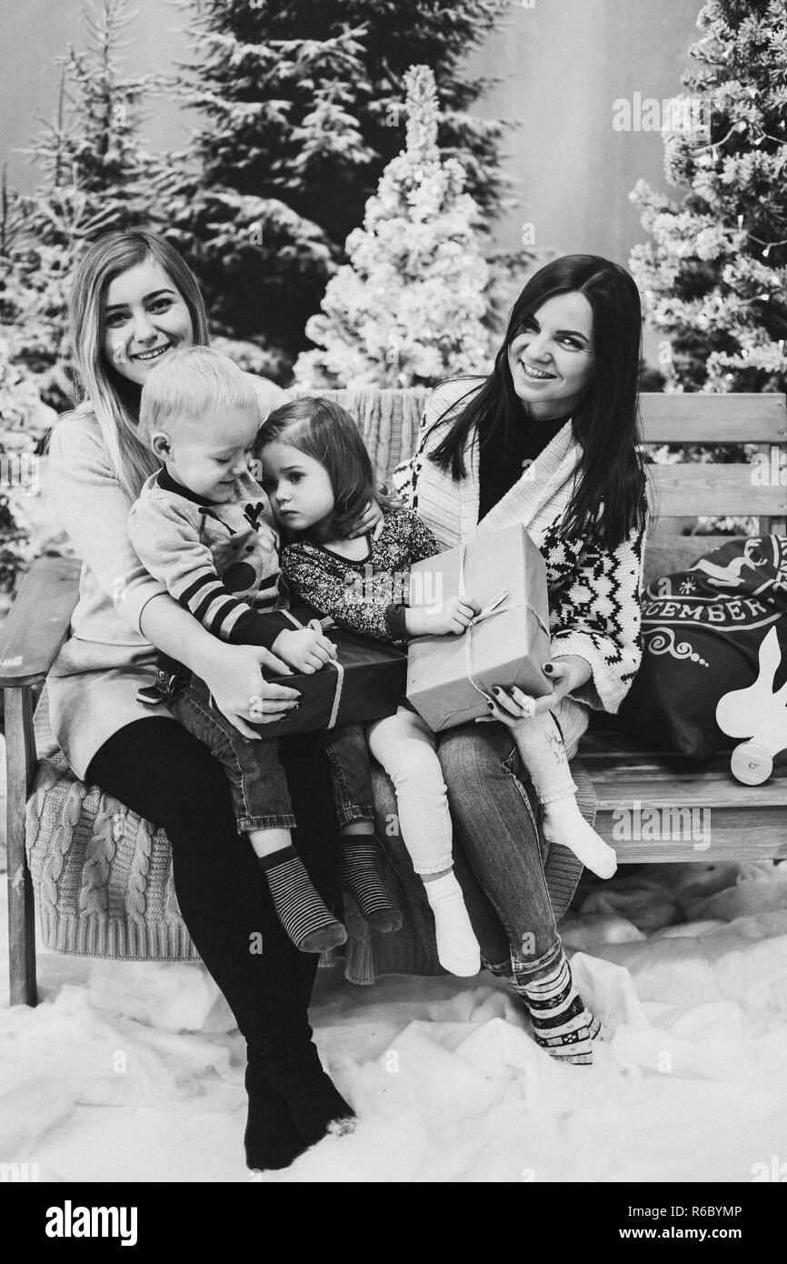 Les mères de deux enfants assis avec mignon et la tenue des cadeaux de Noël. Banque D'Images