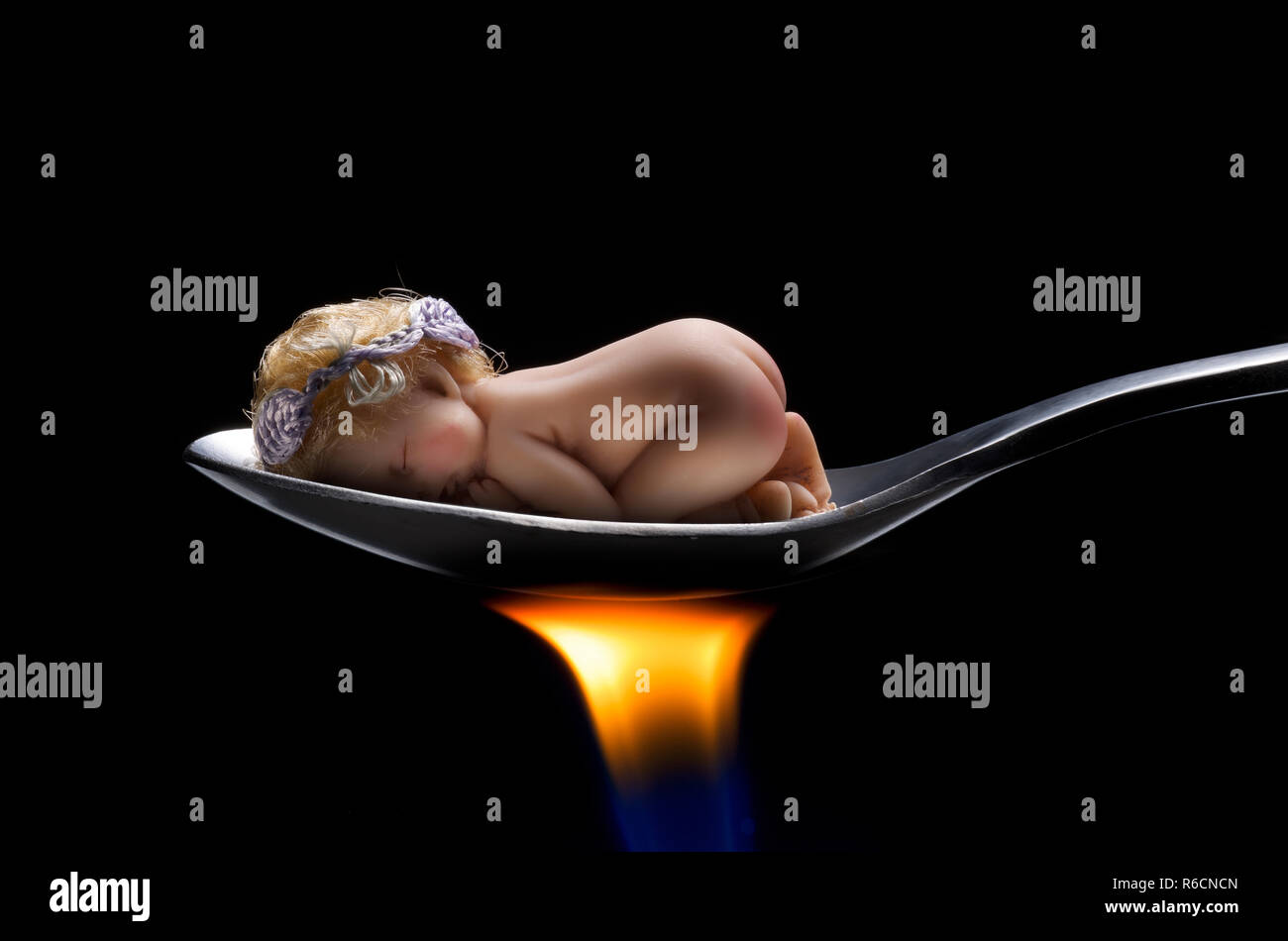 Bébé endormi sur la cuillère sur flamme brûlante Banque D'Images