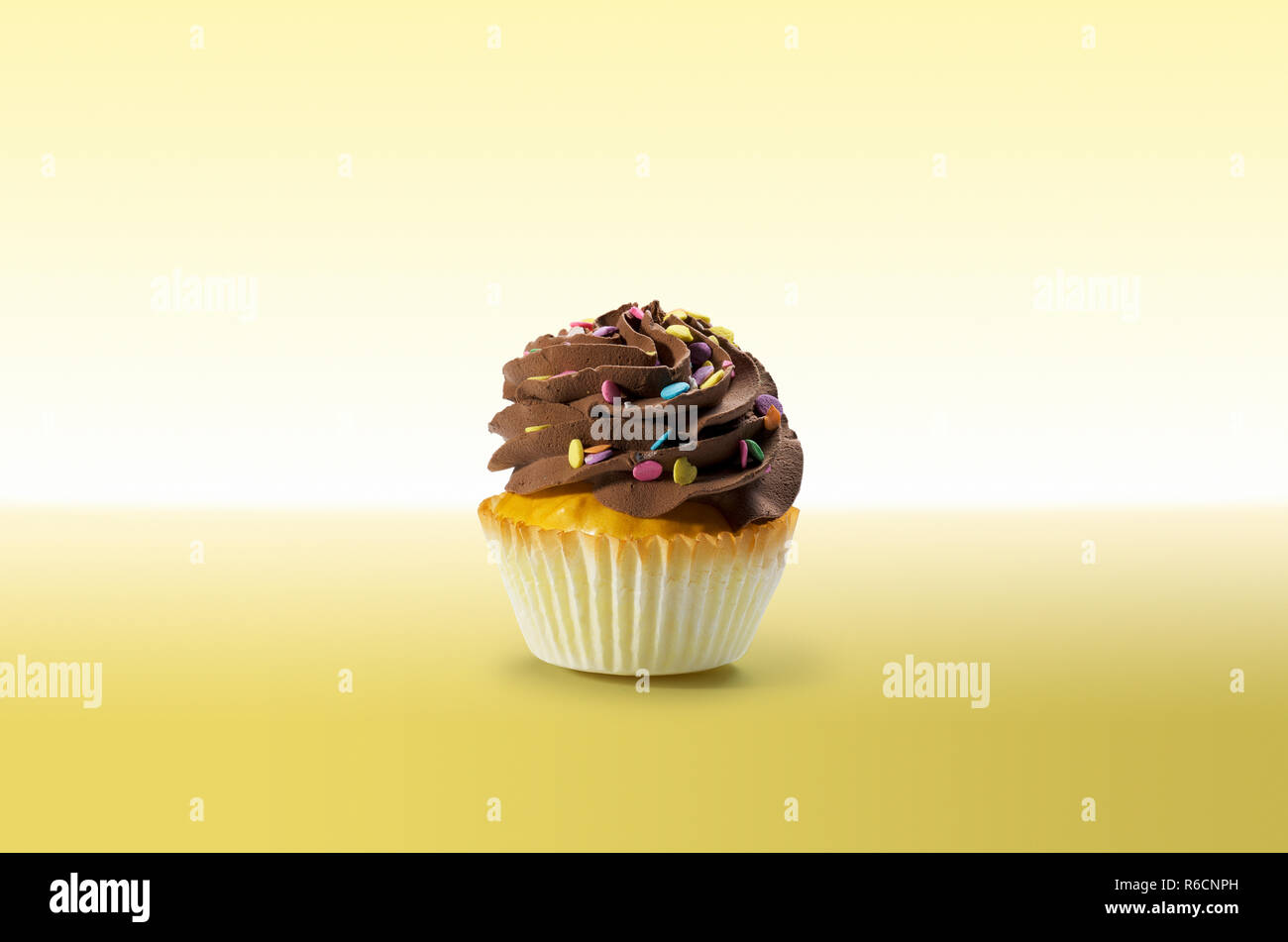 Cupcake chocolat avec glaçage sur une surface jaune Banque D'Images