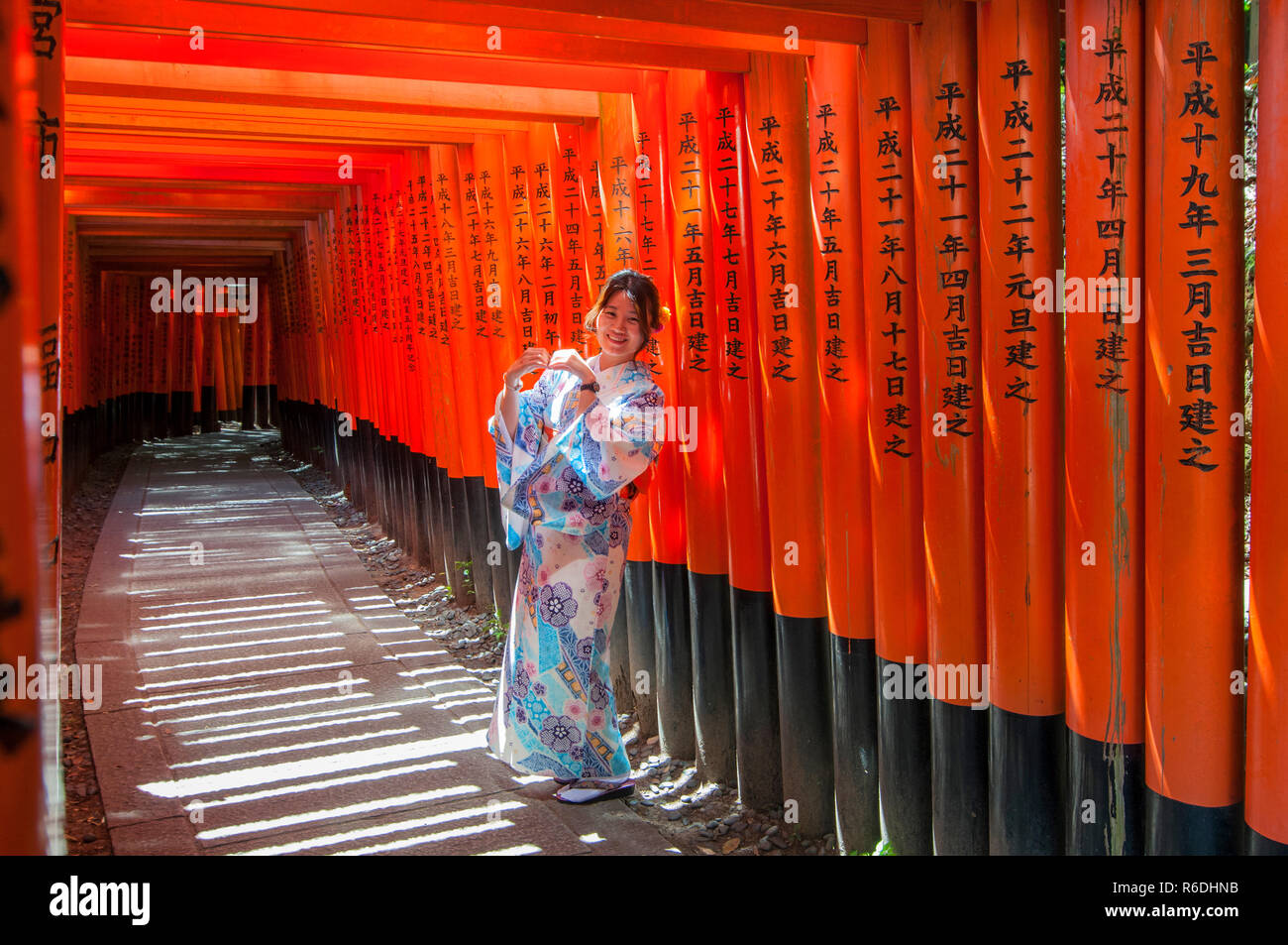 Femme vêtue de costumes traditionnels japonais marcher sous les portes à Tori Fushimi-Inari Shrine Kyoto, Japon Banque D'Images