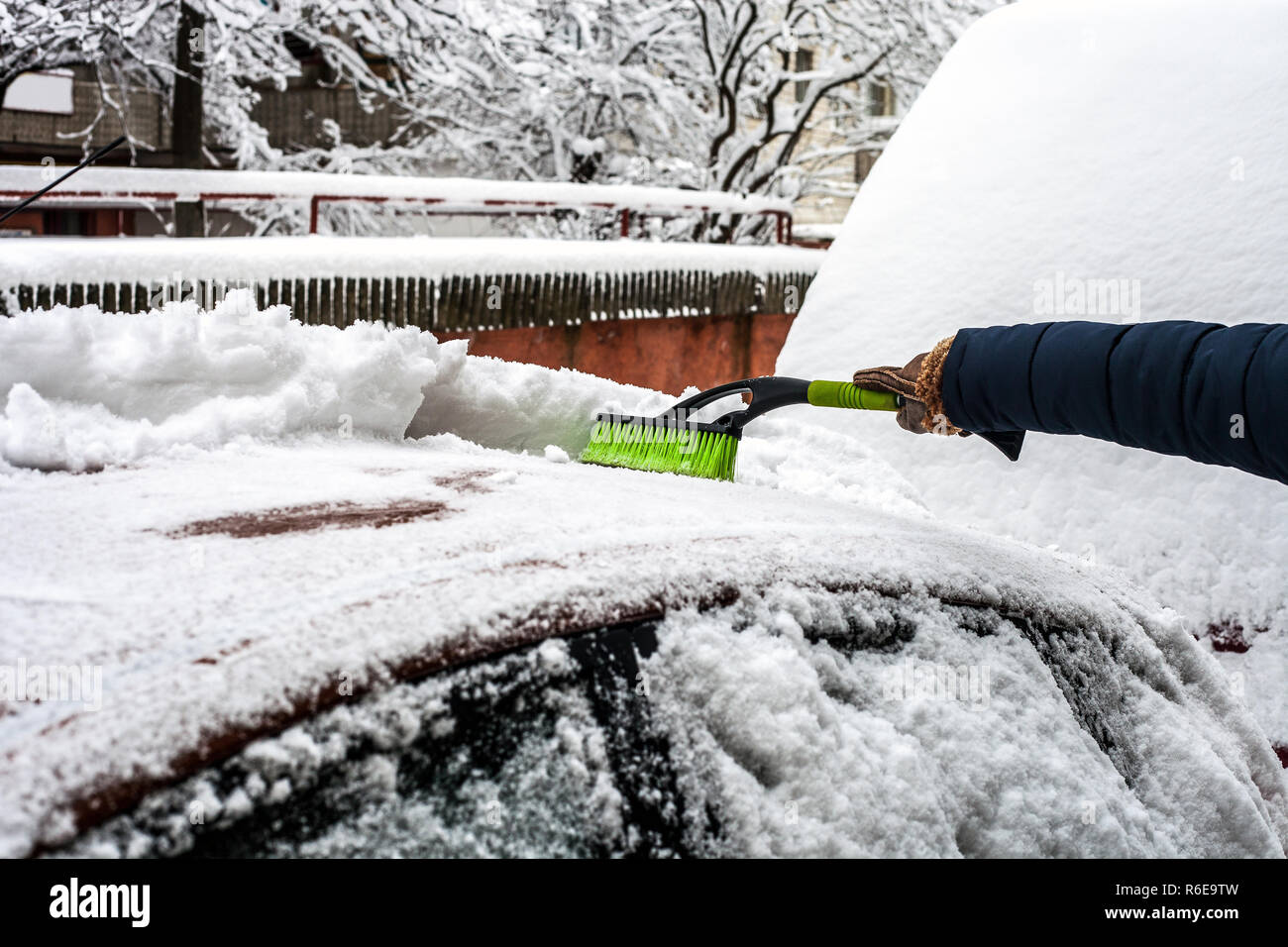 Jeune homme nettoyant sa voiture de la neige à l'aide d'un pinceau. Enlever la neige de l'automobile Banque D'Images