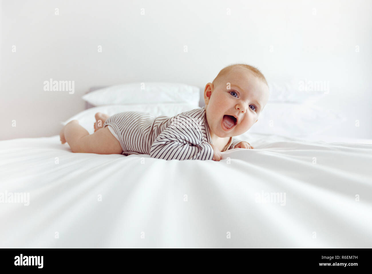 Charmant happy baby sur lit blanc Banque D'Images