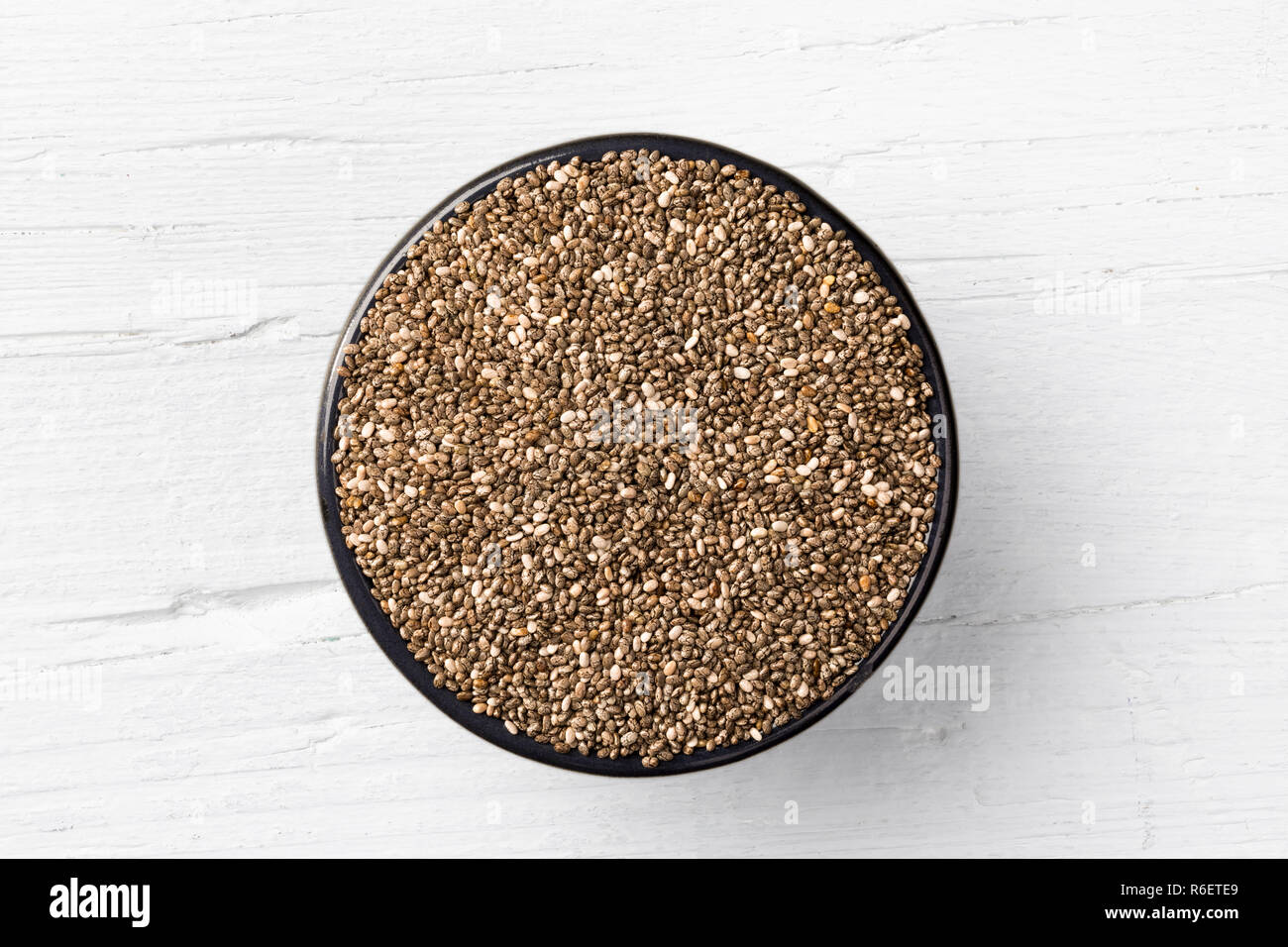 Chia seeds en fonte ronde mug blanc sur fond de bois, vue directement à partir de ci-dessus. Banque D'Images