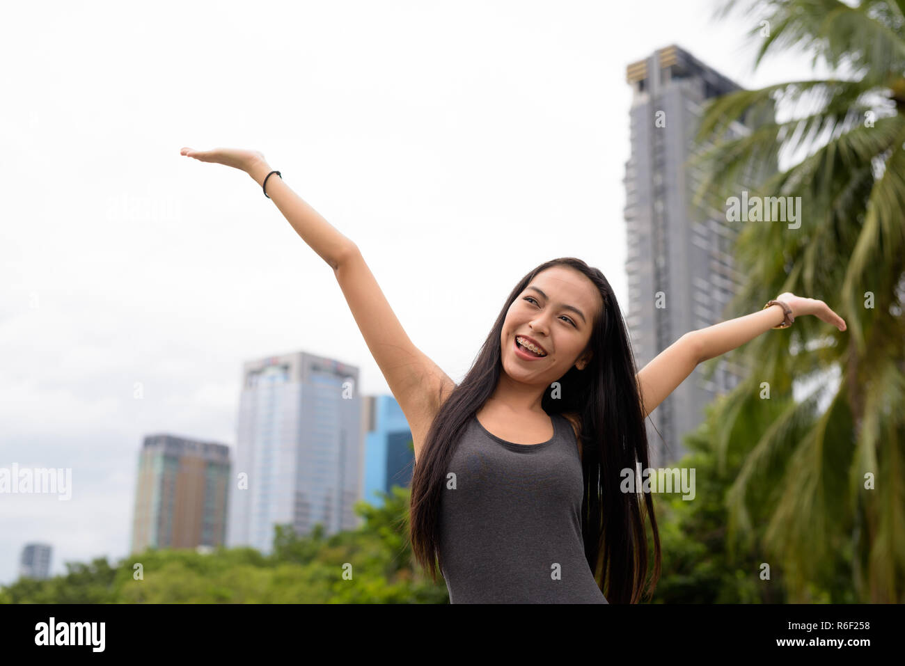Jeune belle Asian woman relaxing at the park with arms raised Banque D'Images