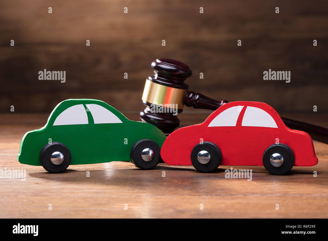 Collision de deux voitures jouet en bois en face de Gavel Banque D'Images