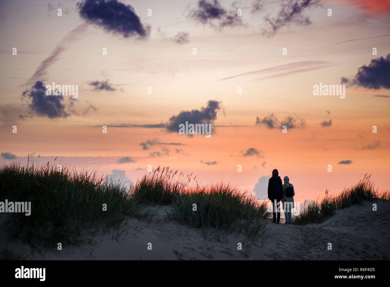 Couple debout à la colline et en regardant le coucher du soleil romantique d'été spectaculaire. ciel du soir. Des souvenirs inoubliables et de moment. Debout au bord de la Banque D'Images