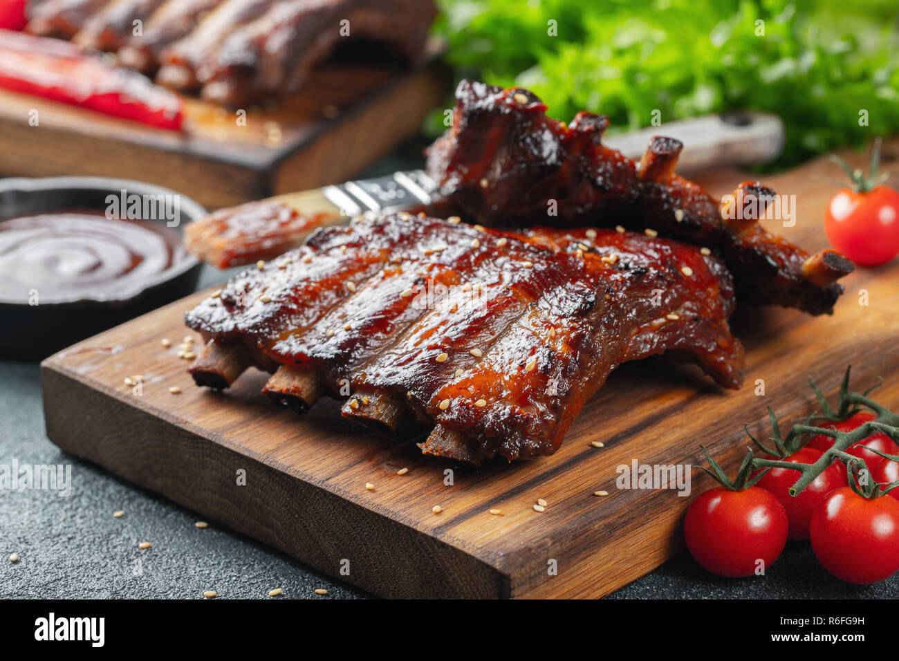 Gros plan du porc grillé à la sauce barbecue et caramélisées dans du miel. Délicieux en-cas à la bière sur une planche en bois pour la production de béton sur fond sombre Banque D'Images