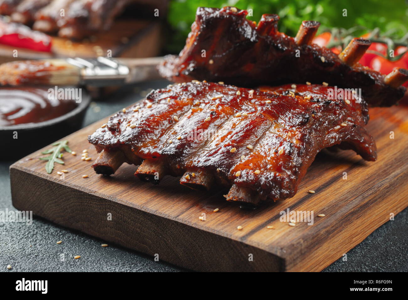 Gros plan du porc grillé à la sauce barbecue et caramélisées dans du miel. Délicieux en-cas à la bière sur une planche en bois pour la production de béton sur fond sombre Banque D'Images
