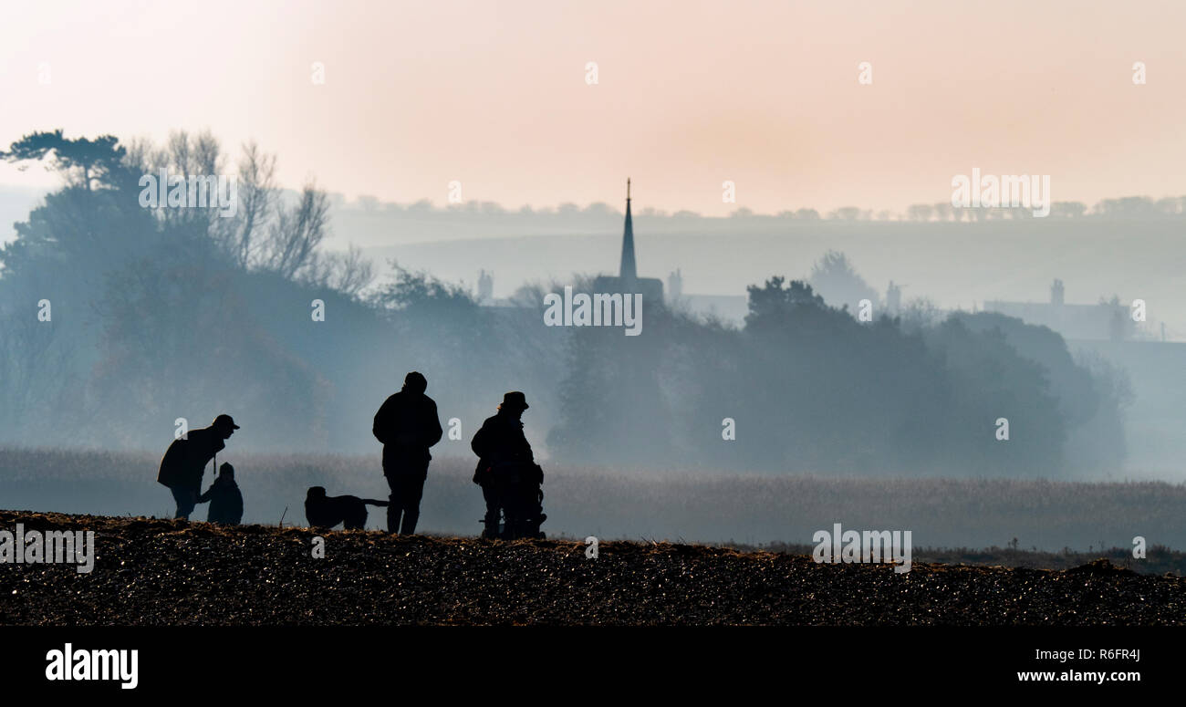 Family on beach village et l'église de Titchwell West Norfolk UK Décembre Banque D'Images