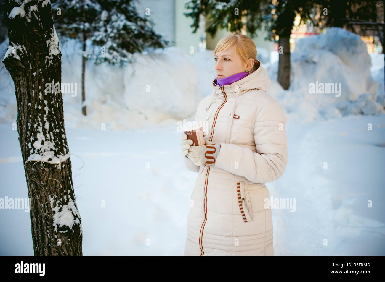 Jeune femme vêtue de vêtements chauds à emporter boire du café de la tasse dans la rue en hiver Banque D'Images