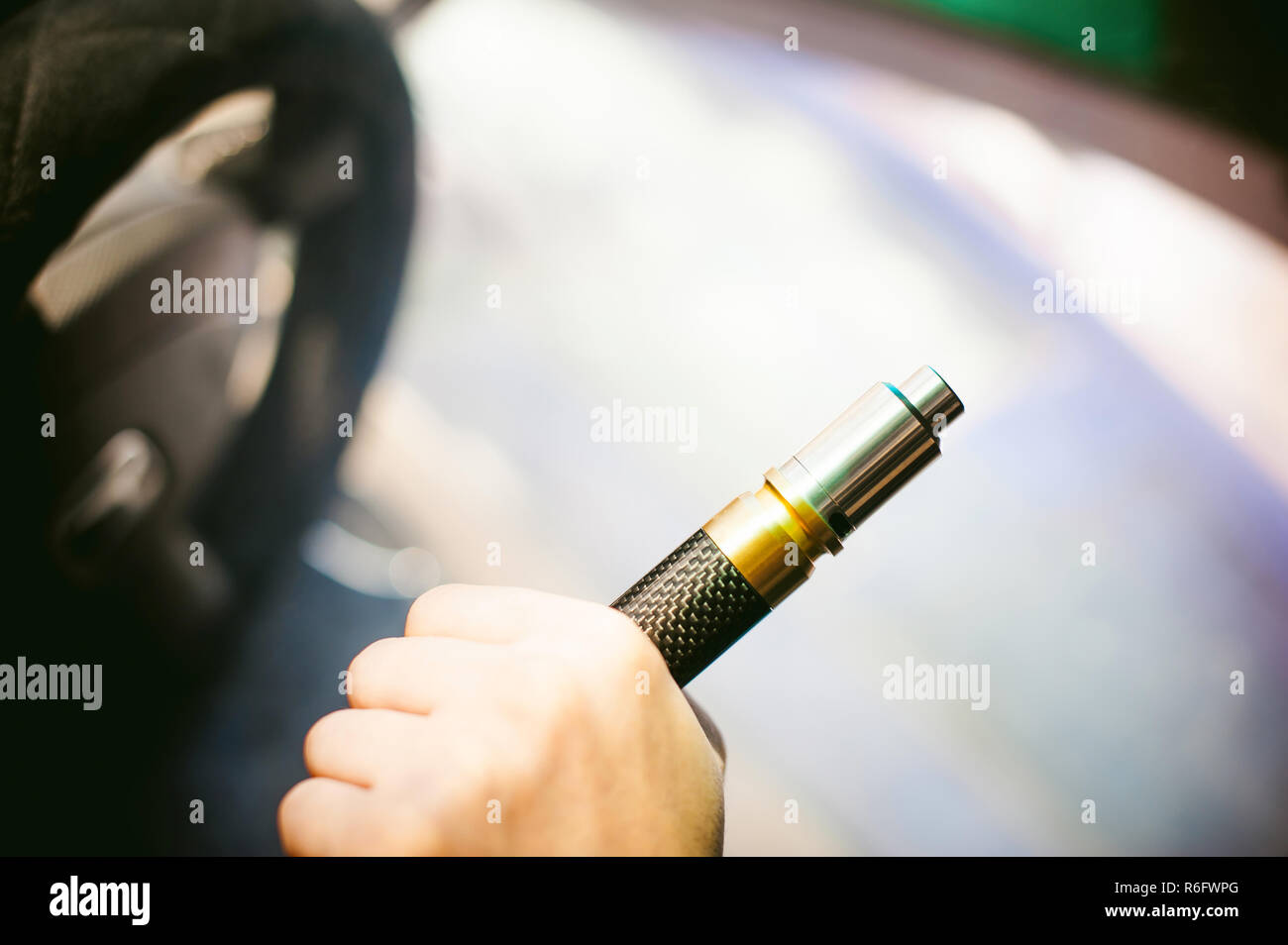 Jeune homme vaper avec barbe vaping mod mécanique. Guy fume une cigarette électronique en soufflant une vapeur de fumée. Tient dans la main sur fond coloré Banque D'Images